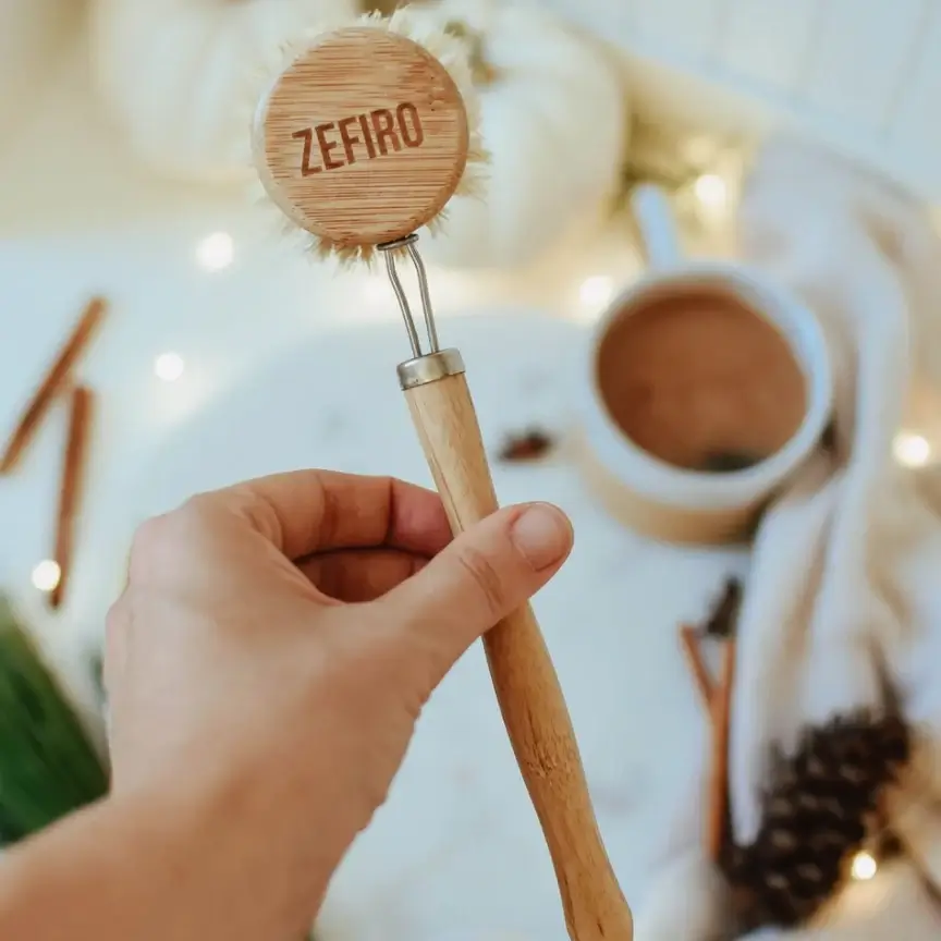 A person's hand holding a bamboo scrub brush.