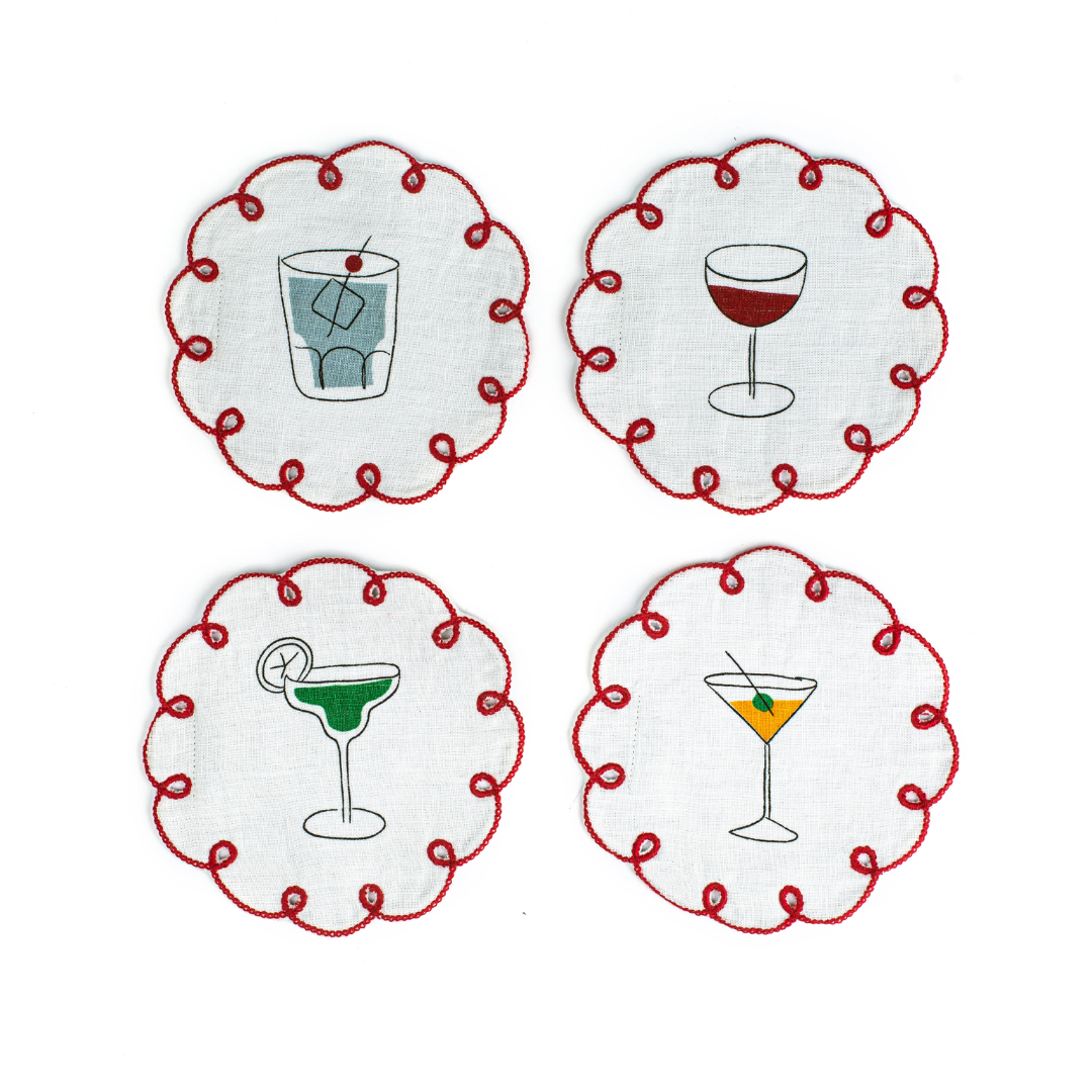 Four circular white linen coasters with a red eyelet border and embroidered drinks in the centre.