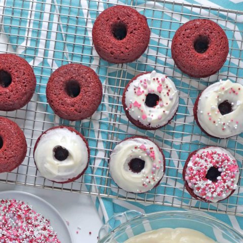 Chocolate donuts, white icing and a bowl of colourful sprinkles