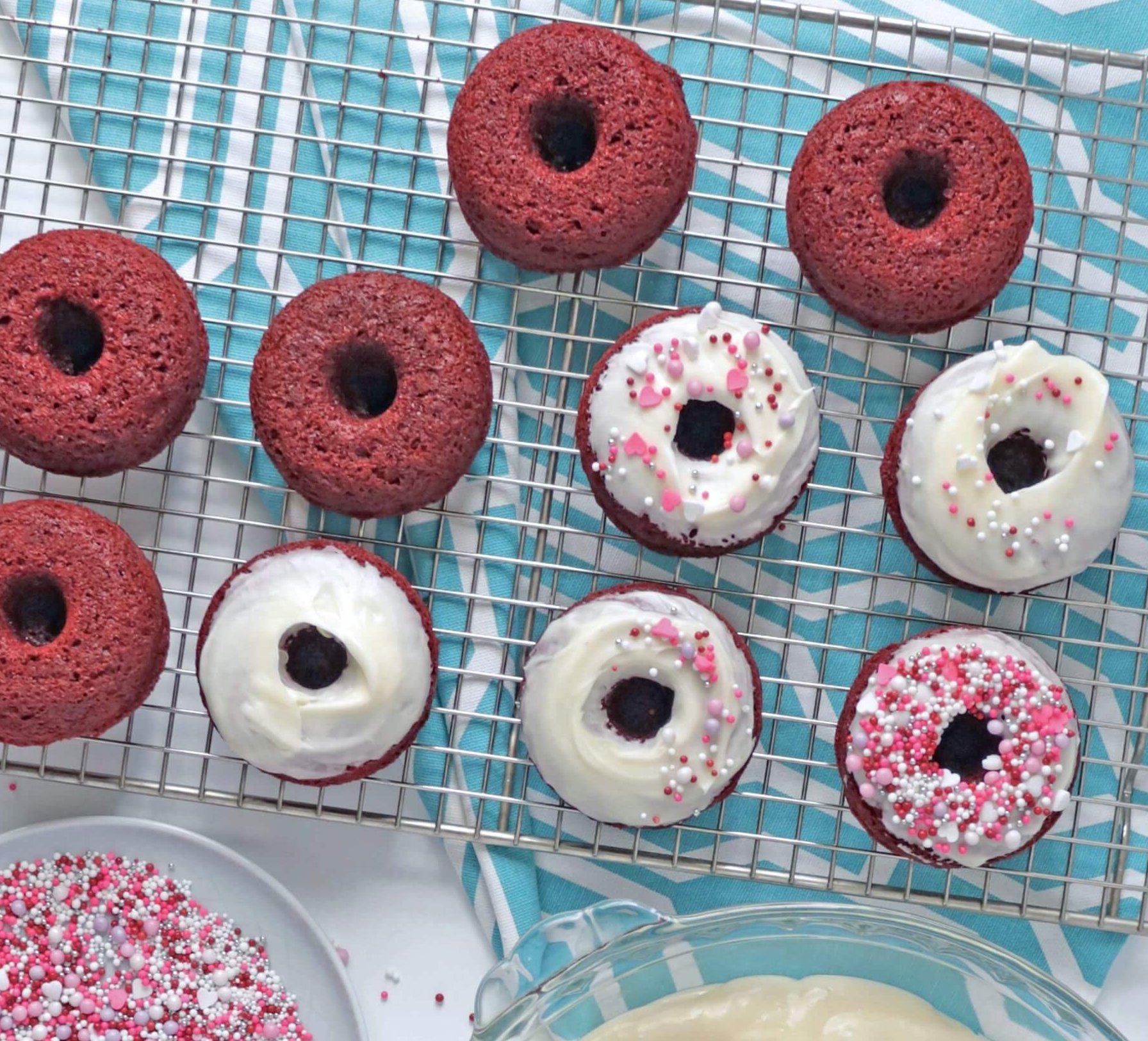 Chocolate donuts, white icing and a bowl of colourful sprinkles