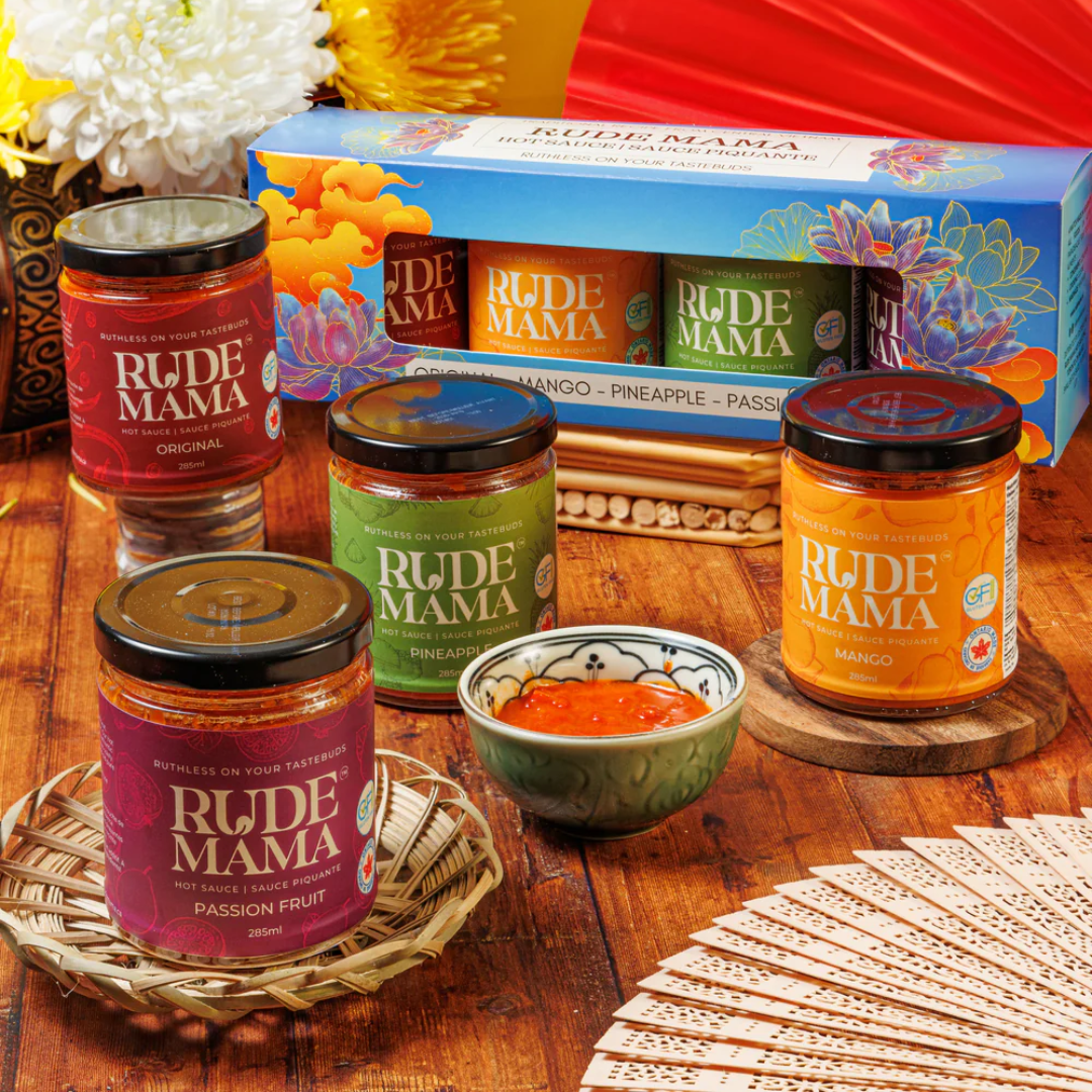 Four jars of hot sauce on a wooden table with a gift set of four hot sauces.