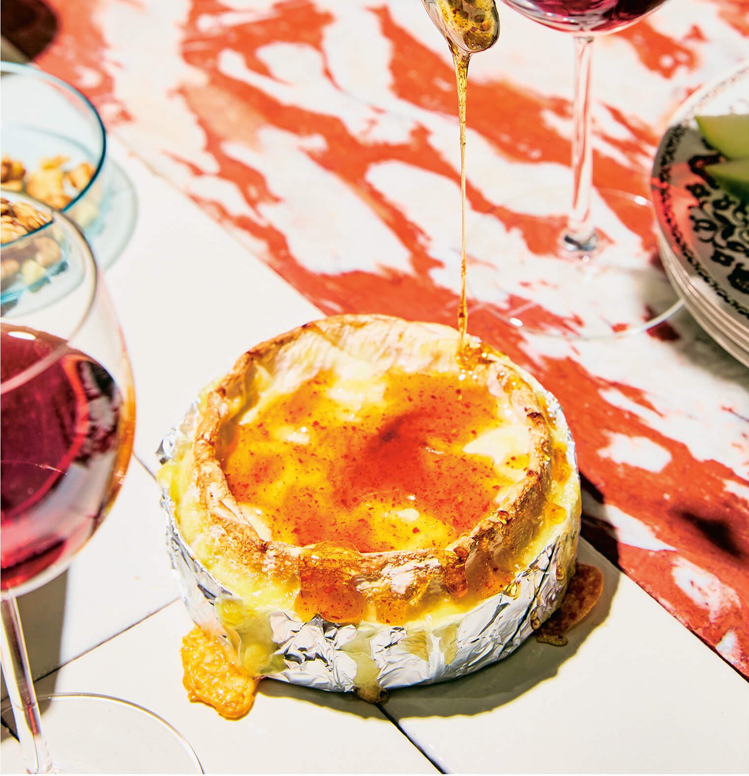 Round brie cheese being drizzled with honey