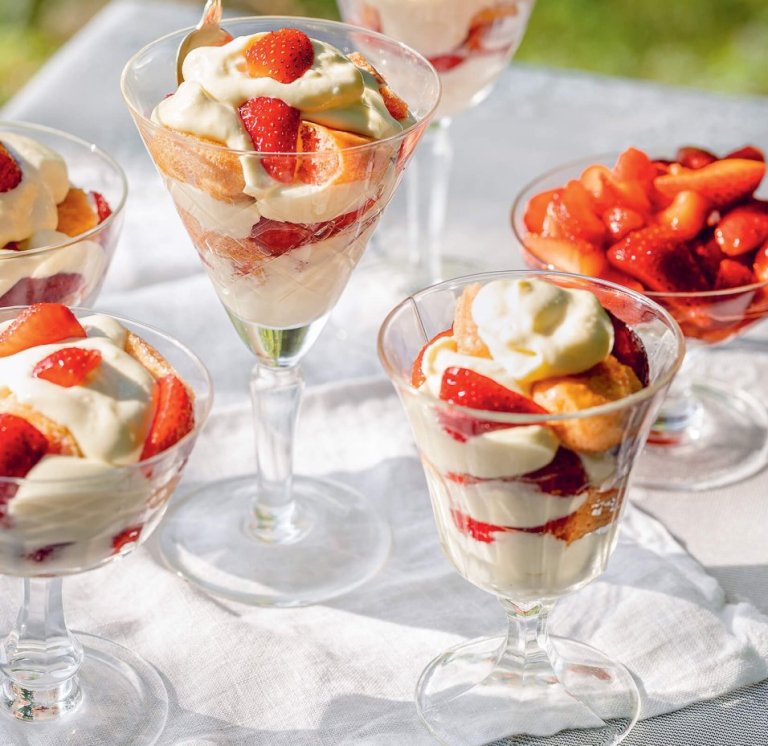 A white cloth on grass laid with strawberry tiramisu parfaits