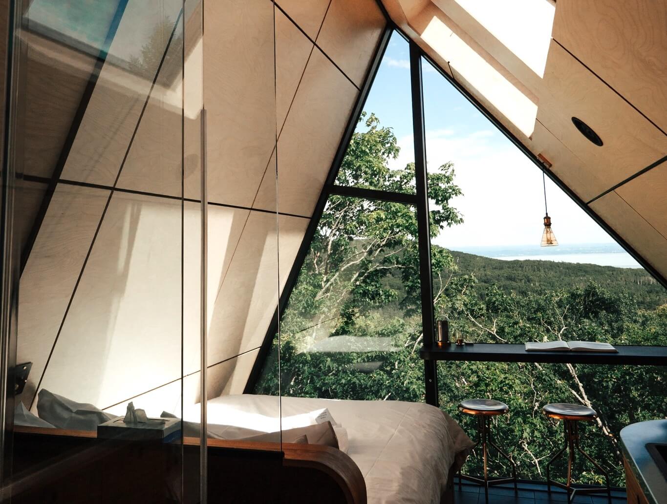 A modern hotel room panelled in wood overlooking a green forest.