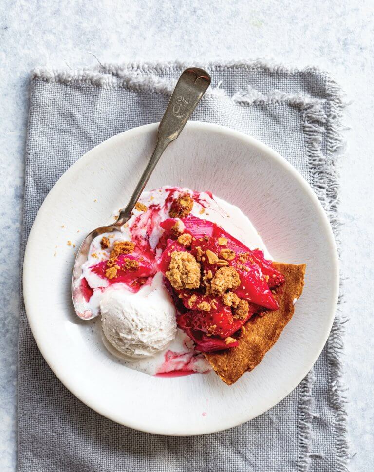 Slice of gluten-free strawberry rhubarb crumble pie served with vanilla ice cream.