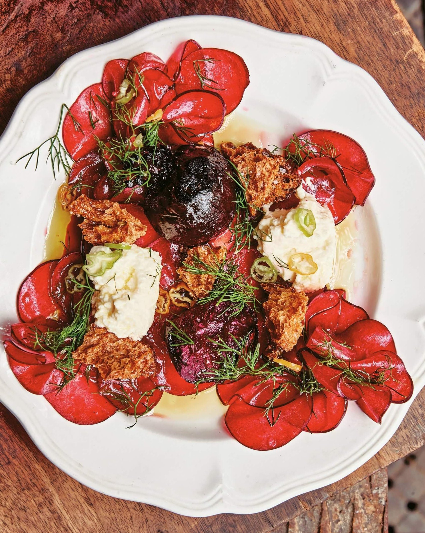 A white plate with a colourful beet salad on a wooden table