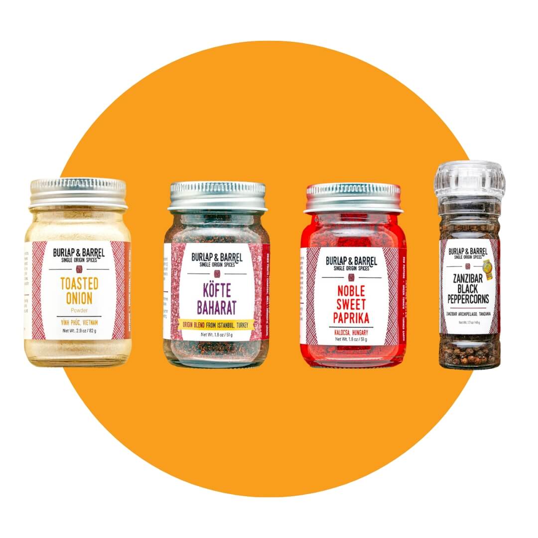 Four spice jars and a pepper grinder on an orange circle graphic