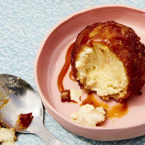 A scoop of fried ice cream with caramel sauce on a light pink plate