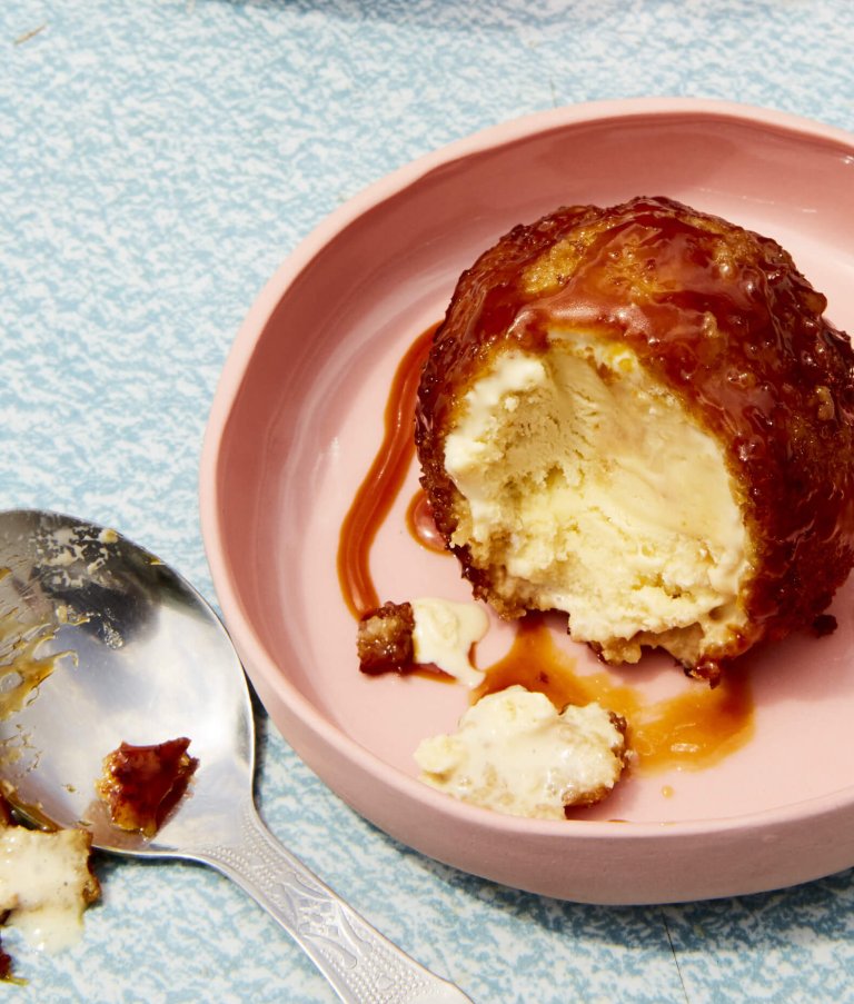 A scoop of fried ice cream with caramel sauce on a light pink plate