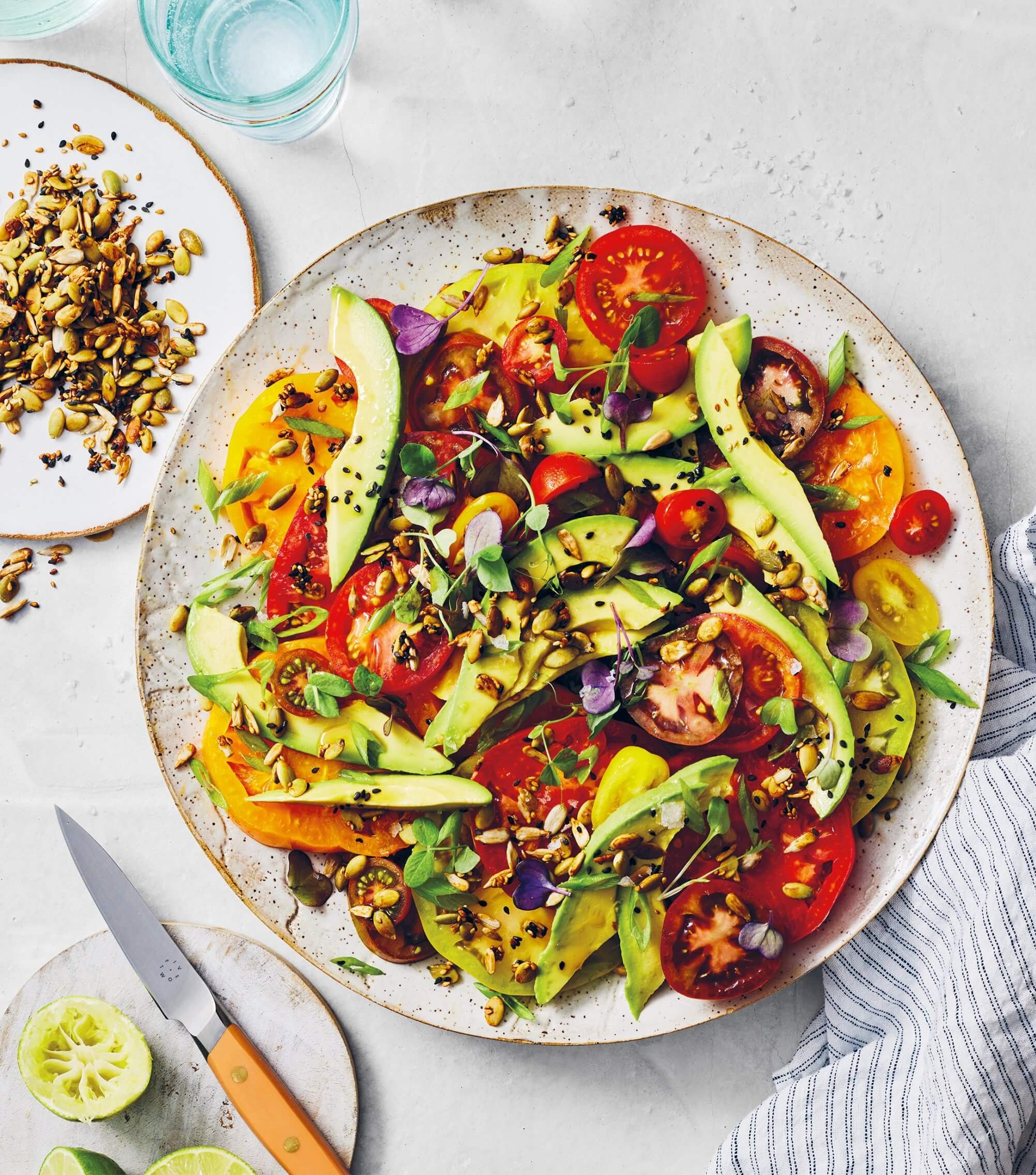 A white plate with an avocado, tomato and grain salad