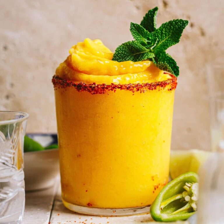 Frozen mango mezcal margarita in a glass with a salted rim.