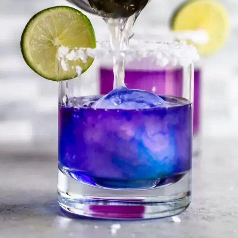 Purple colour-changing margarita being poured into a cocktail glass.
