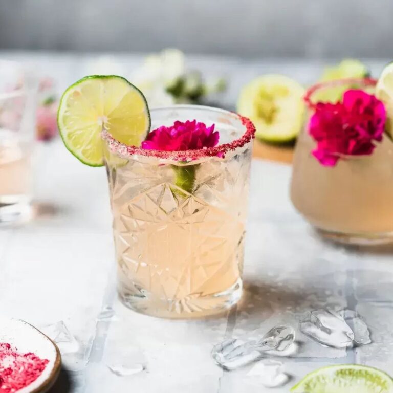 Rosé margarita garnished with a lime wheel and edible flower.