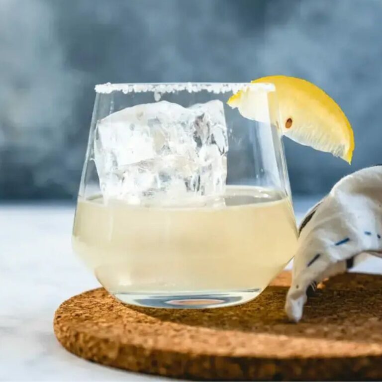 Lemon margarita served over a large ice cube with a lemon wedge.