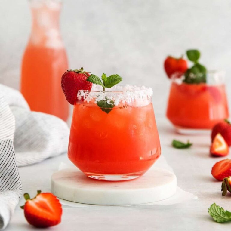 Fresh strawberry margarita in a salt-rimmed glass garnished with strawberries and mint.