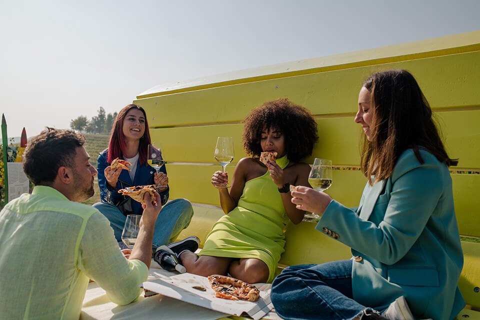 A group of people drinking wine in front of a yellow van