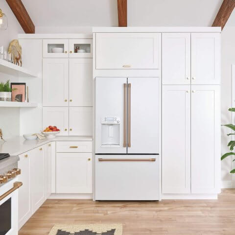 A kitchen with white cabinetry and a white fridge