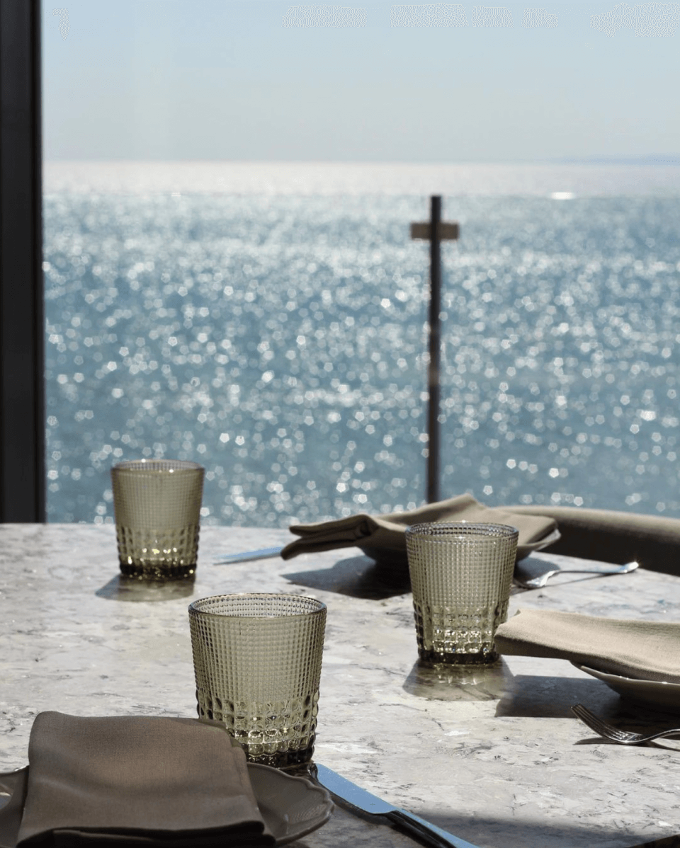 A table set with green glasses and a lake view visible in the background