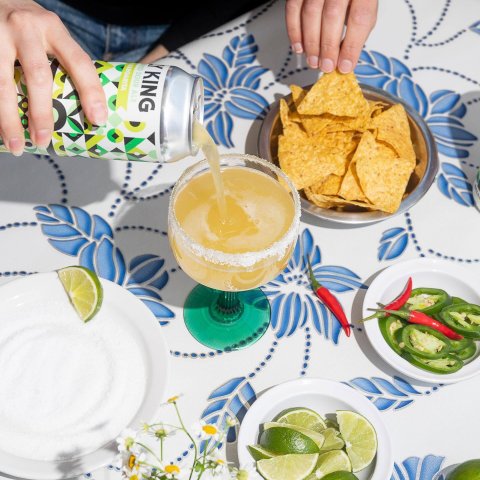 A person pouring beer into a glass and eating nachos