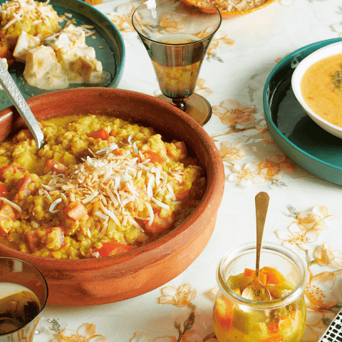 A table with a floral tablecloth and multicoloured dishes with rice and curry