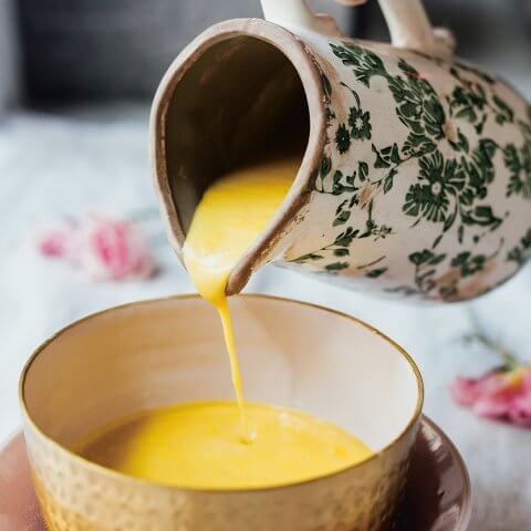 Soup being poured from a ceramic pitcher into a bowl