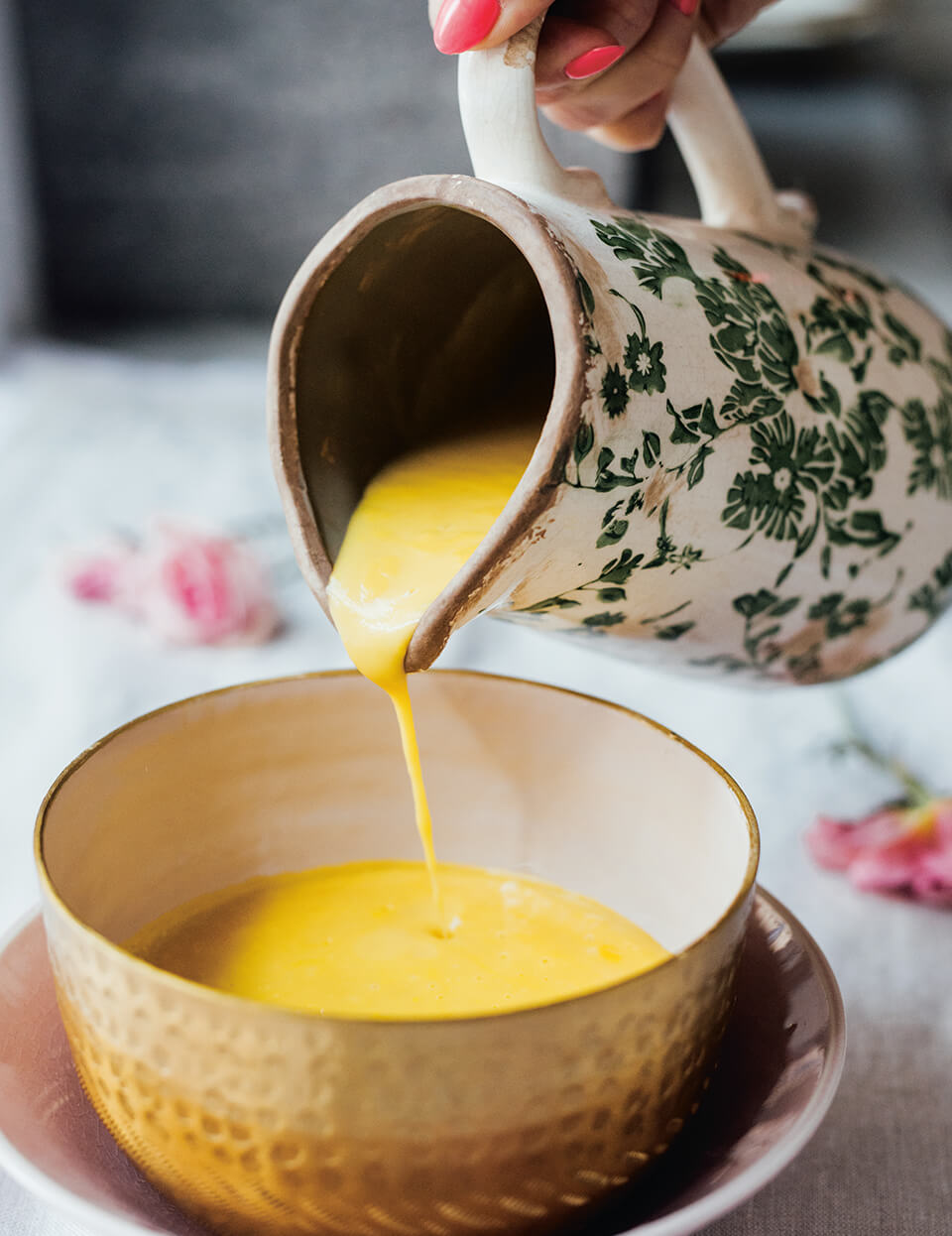 Soup being poured from a ceramic pitcher into a bowl