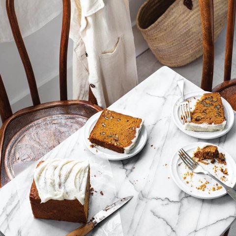 A table and wooden chairs with plates of pumpkin load with white frosting