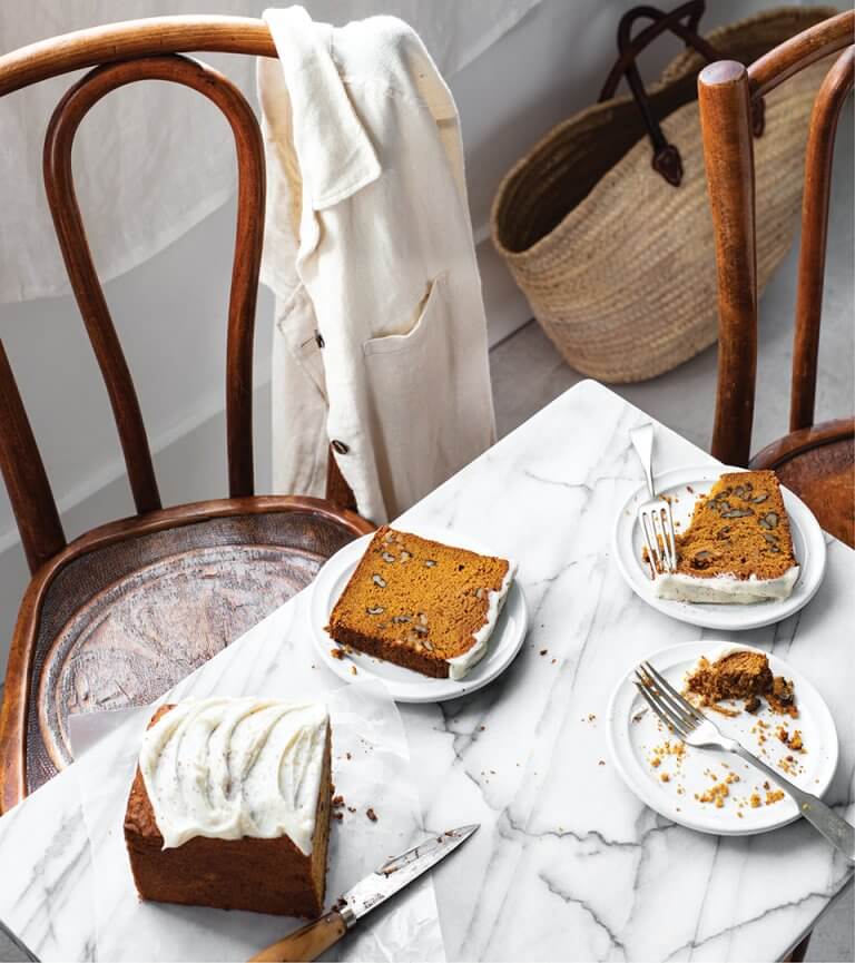 A table and wooden chairs with plates of pumpkin load with white frosting