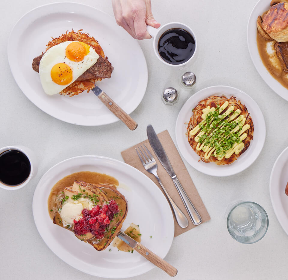 A table with various diner breakfast items and cups of coffee