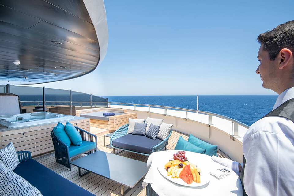 A butler walking a tray of food onto a cruise ship deck