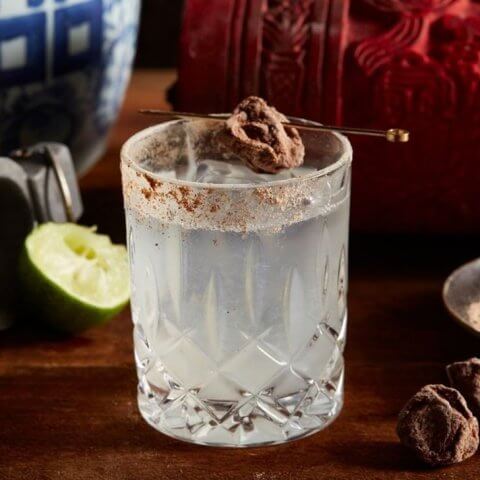A cocktail garnished with a piece of salted plum