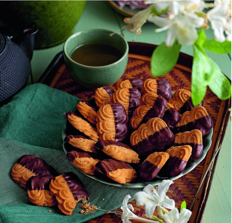 A dish of chocolate-dipped cookies on a wooden tray
