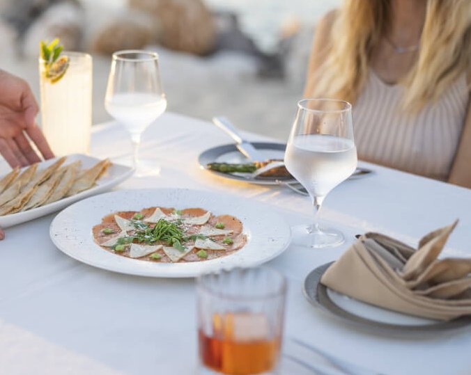 Woman sitting at table by beach with food