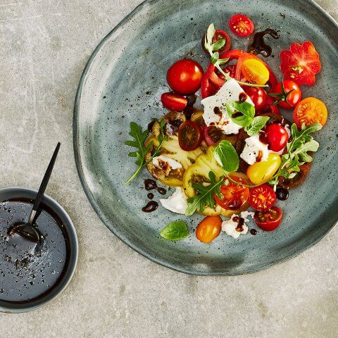 A plate with salad and a small dish of dressing next to it