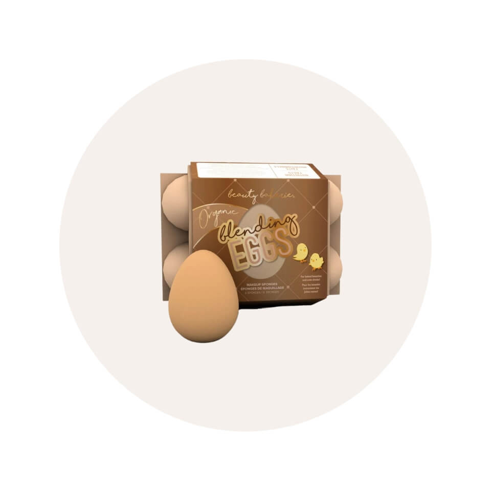 A makeup sponge and small brown egg carton over a cream-coloured circle