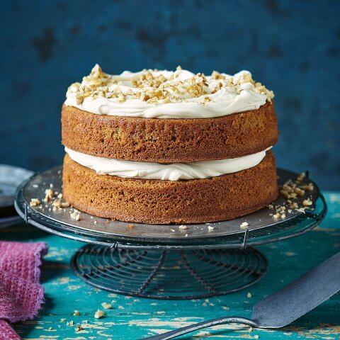 A two-layer cake with white frosting on a blue cake stand and table