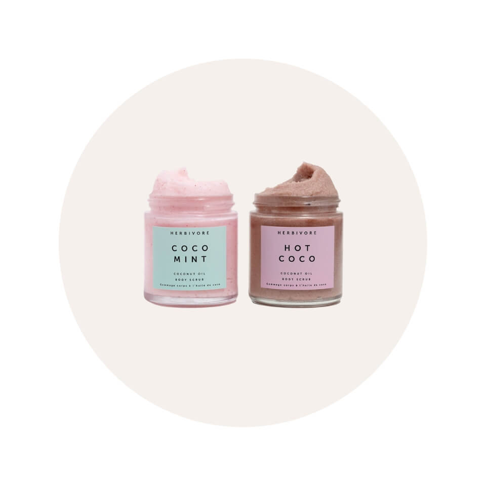 Two jars of body scrub over a cream-coloured circle graphic