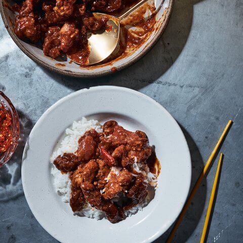 A serving dish with orange chicken and a dish of it over rice