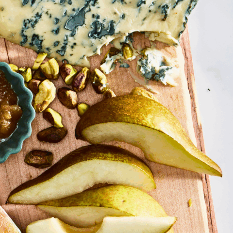 Bosc pears and blue cheese with pistachios on a wooden board
