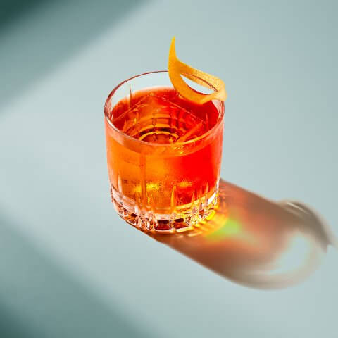 A Negroni on a light blue surface