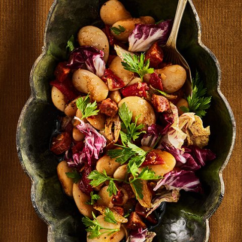 A dish with butter bean salad on a mustard-coloured cloth