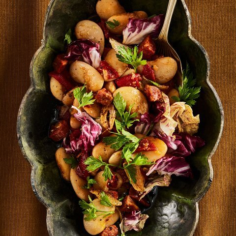 A dish with butter bean salad on a mustard-coloured cloth