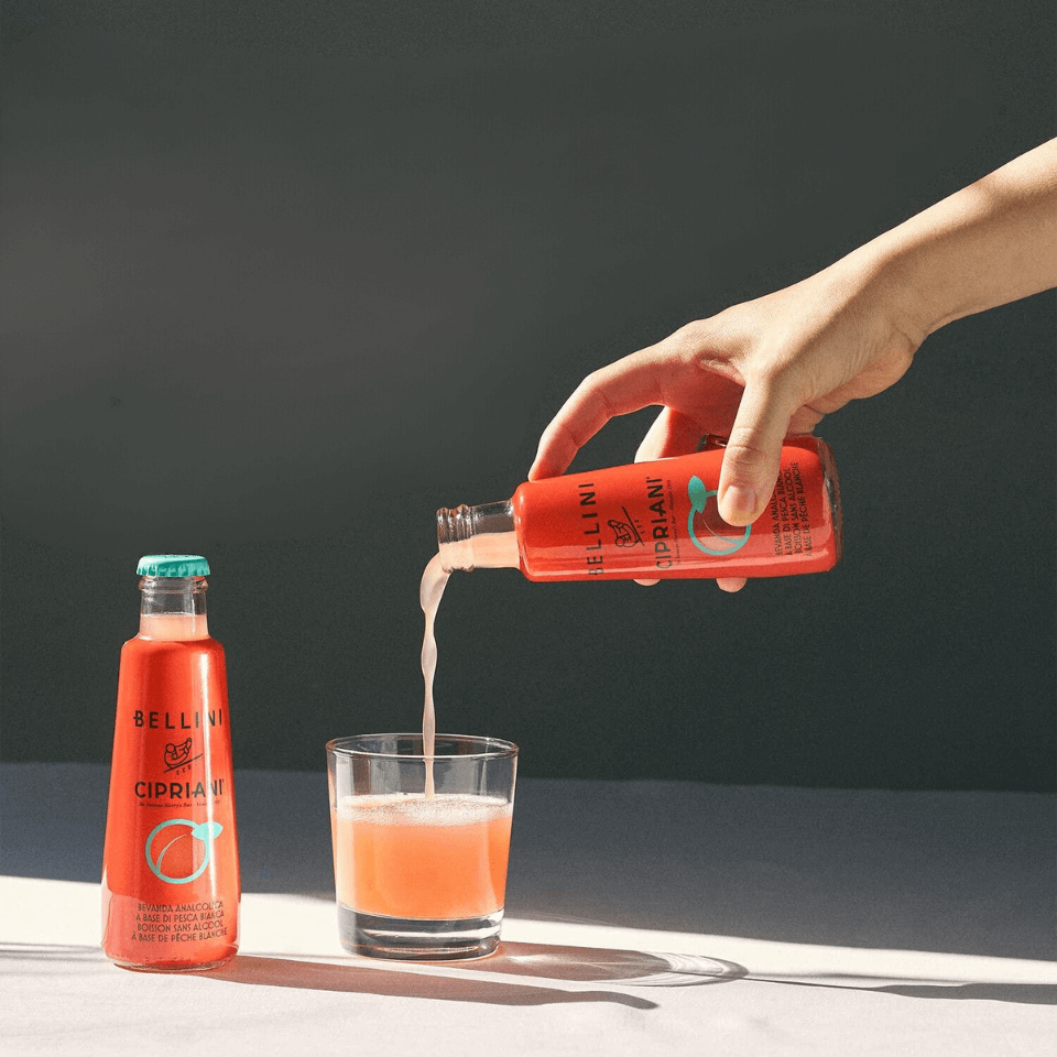 A person's hand pouring a bottled cocktail into a glass