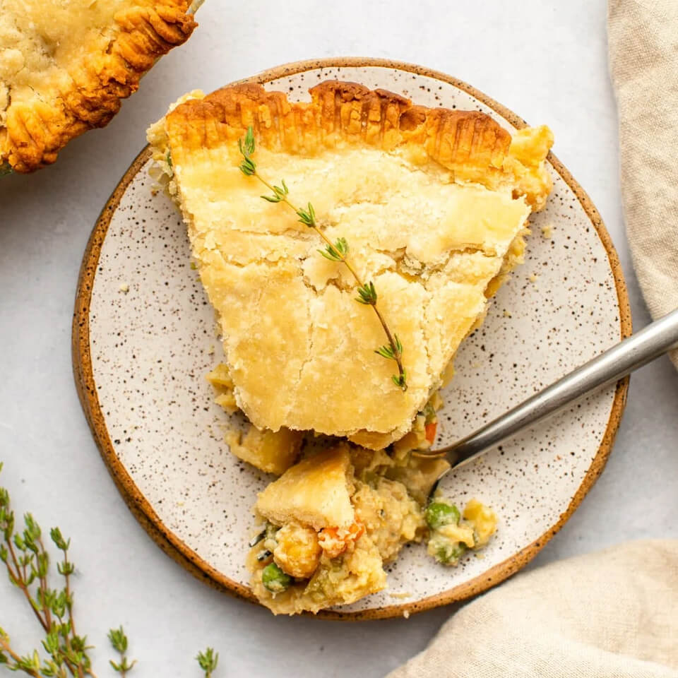 A slice of pot pie on a speckled plate