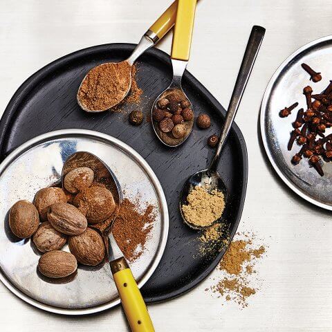 A black plate with yellow-handled spoons and various spices