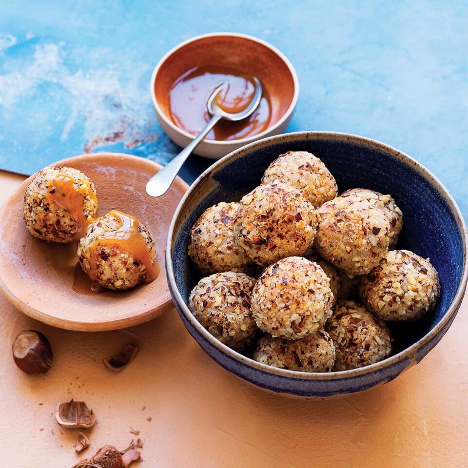 A bowl of dessert bites with a dish of caramel sauce