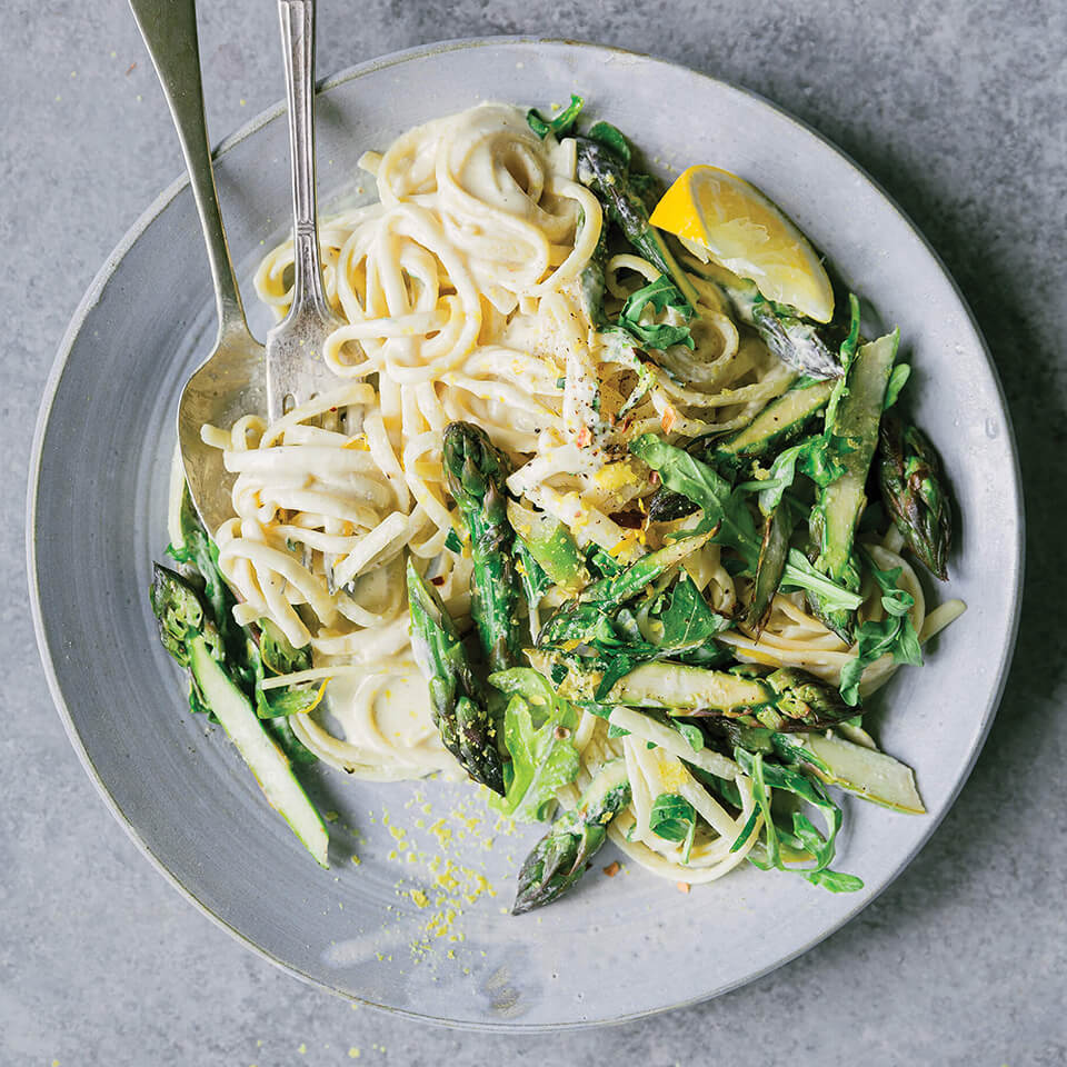 A plate of pasta with asparagus and cream sauce
