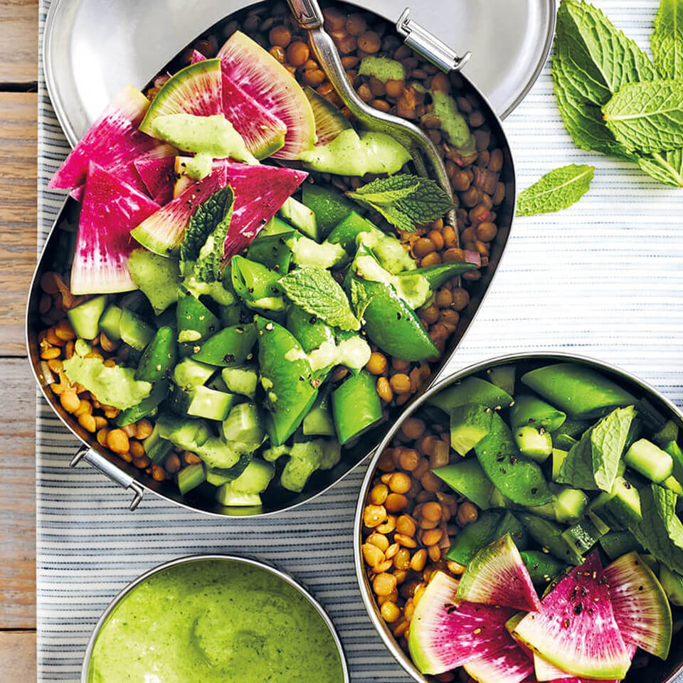 Containers filled with lentil salad and a bowl of green sauce