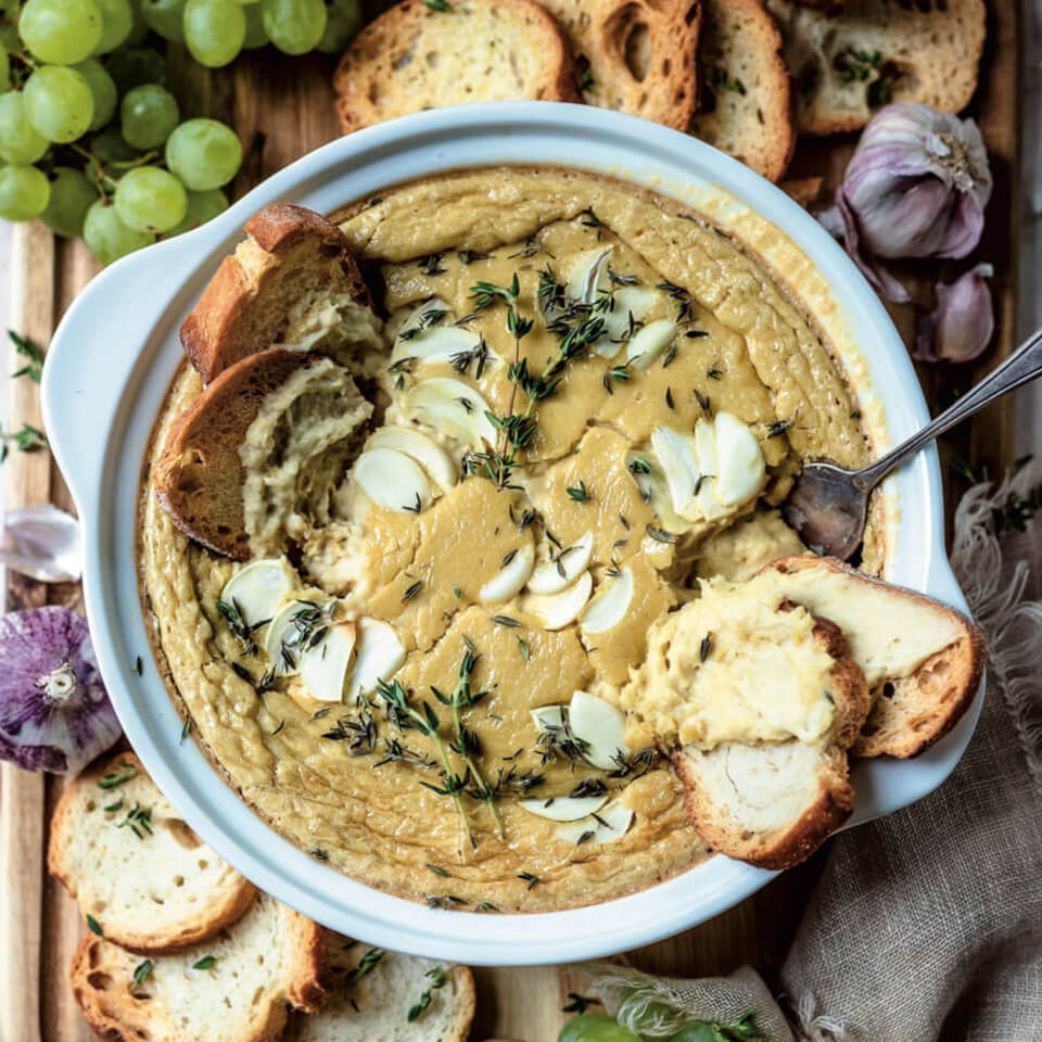 A brie dish on a fruit and cracker board