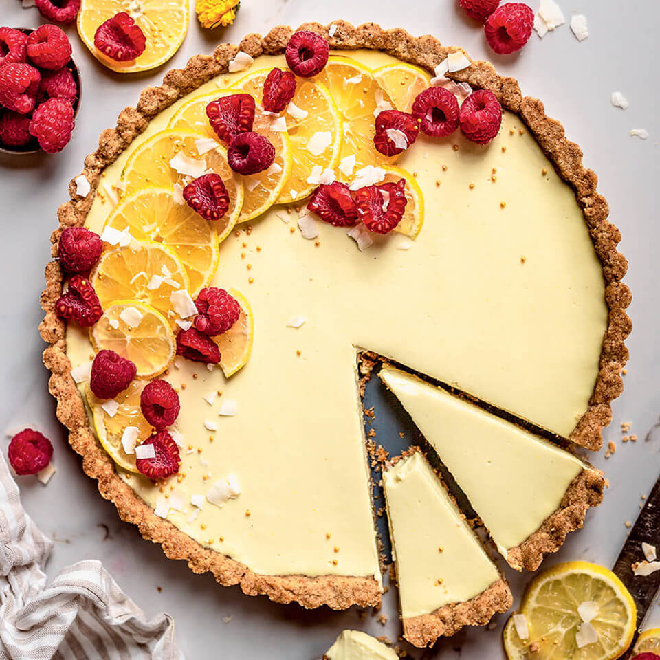 A lemon tart with raspberries scattered over it